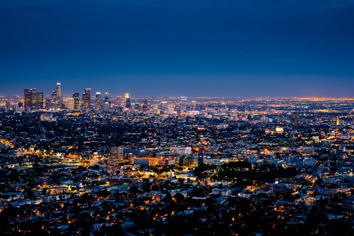 Office towers at night, windows still lit — the system runs while the firm sleeps